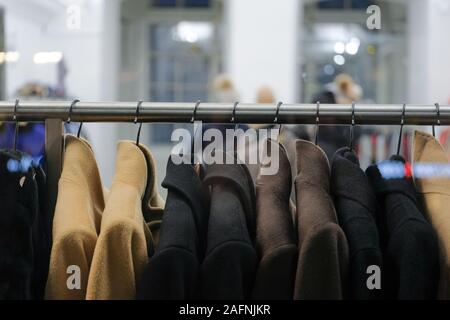 Kleiderbügel mit verschiedenen Mäntel auf der Schaufenster. Close Up. Stockfoto