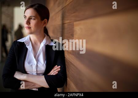 Geschäftsfrau steht Arm gekreuzt lehnte sich gegen eine Wand. Stockfoto