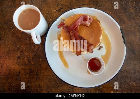 Ein Stapel von amerikanische Pfannkuchen mit Speck und Ahornsirup. Stockfoto