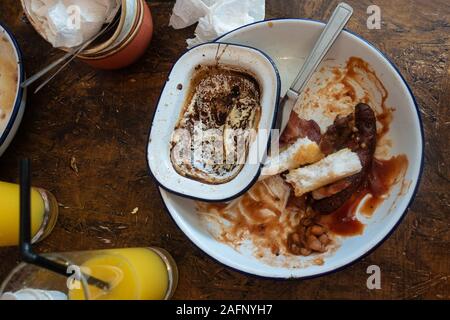 Eine leere, schmutzig, rustikalen weiße Platte auf einem holztisch am Ende einer Mahlzeit. Stockfoto