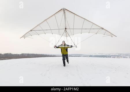 Glücklich Mann hält Vintage glider Flügel hängen. Drachenfliegen im Winter. Stockfoto