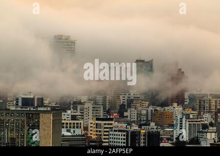 Gebäude, die von Nebel am Ende eines warmen Nachmittag im nördlichen Teil der Stadt Quito umgeben Stockfoto