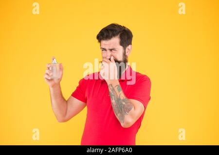 Unangenehmer Geruch. Hygiene und Gesundheit. bärtiger Mann halten Parfüm Flasche. perfektes Aroma für echte Männer. brutale hipster Geruch wählen. reifer Mann empfohlen Deodorant. Mode Köln Flasche. mag es nicht. Stockfoto