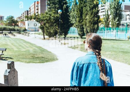 Junge Frau von hinten Gehen durch einen Park an einem sonnigen Tag Stockfoto