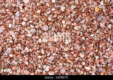 Rot und Weiß Granit feinen Kies. Einfache Stein Hintergrund mit roten Steinen. Stein Textur. Blick von oben auf die Erde Dekor für Garten mit bunten natürliche Stockfoto