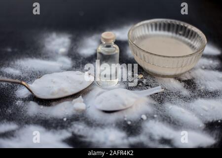 Gesichtsmaske oder Packung Backpulver in eine Glasschüssel auf Holz- Oberfläche zusammen mit Pulver und einige Kokosöl in einem Glasfläschchen. Verwendet für Stockfoto