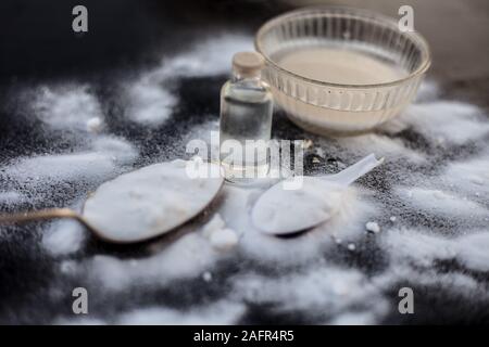 Gesichtsmaske oder Packung Backpulver in eine Glasschüssel auf Holz- Oberfläche zusammen mit Pulver und einige Kokosöl in einem Glasfläschchen. Verwendet für Stockfoto