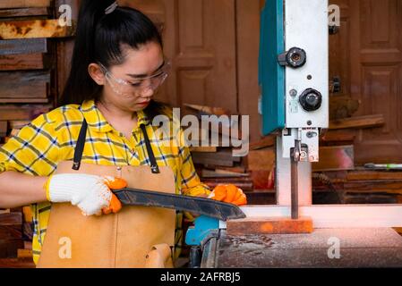 Frauen stehen ist Handwerk Holz arbeiten an einer Werkbank mit Bandsägen power tools bei Tischler Maschine in der Werkstatt, Arbeiter sägen Bretter aus wi Stockfoto