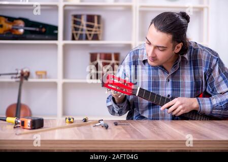 Die junge schöne Handwerker Reparatur Gitarre Stockfoto