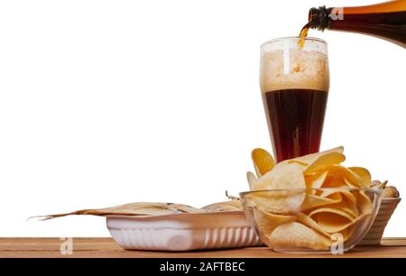 Bier ist in ein Glas mit einem Imbiss auf den Tisch schüttete Stockfoto