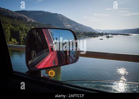 Wenn Sie in einem Seitenspiegel auf die Straße zurückblicken und auf die Columbia Gorge blicken, die auf einem Straßenausflug über eine Brücke führt. Stockfoto