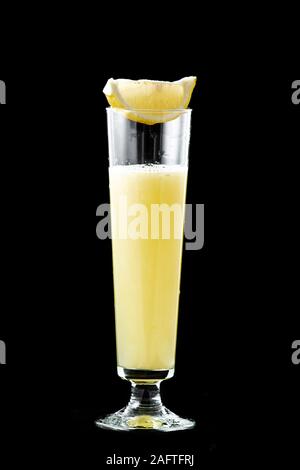 Frisch gepressten Zitronensaft in ein Glas, oben auf dem Glas ist ein Stück frische Zitrone. Auf schwarzem Hintergrund isoliert. Stockfoto