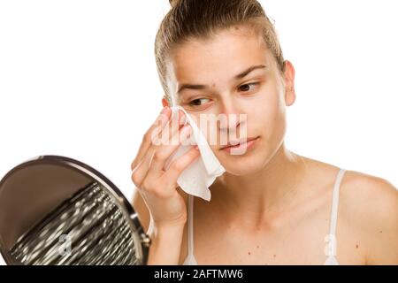 Junge Frau ihr Gesicht Reinigung mit einem feuchten Tuch auf weißem Hintergrund Stockfoto