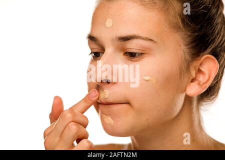 Porträt der jungen Frau, die Liquid Foundation mit Pinsel auf weißem Hintergrund Stockfoto