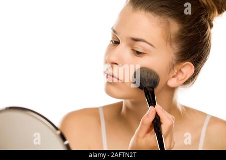 Porträt der jungen Frau Anwendung Powder Foundation mit Pinsel auf weißem Hintergrund Stockfoto