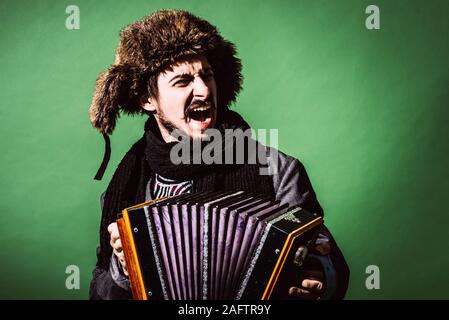 Positiver Mann mit Akkordeon posiert im Studio Stockfoto