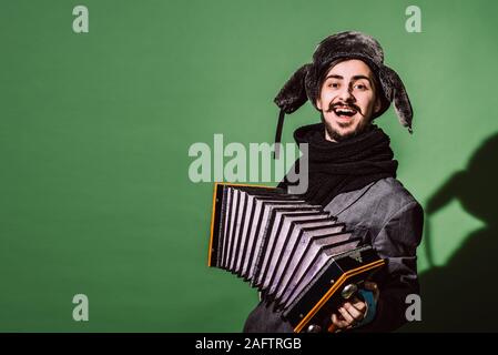 Positiver Mann mit Akkordeon posiert im Studio Stockfoto