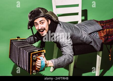 Positiver Mann mit Akkordeon posiert im Studio Stockfoto