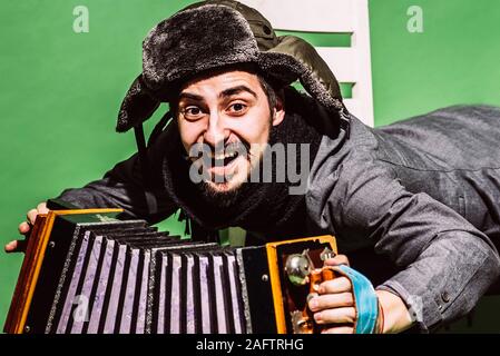 Positiver Mann mit Akkordeon posiert im Studio Stockfoto