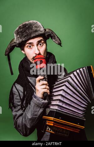 Positiver Mann mit Akkordeon posiert im Studio Stockfoto