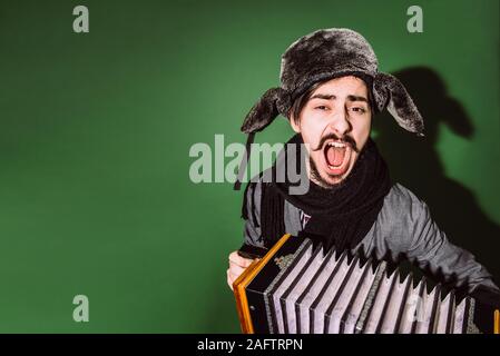 Positiver Mann mit Akkordeon posiert im Studio Stockfoto