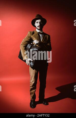 Mann in Anzug im Studio mit Koffer in der Hand posieren Stockfoto