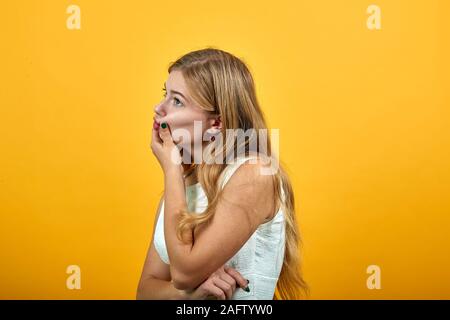 Enttäuscht kaukasische Frau mit Finger auf Wangen, Lippen geklemmt Stockfoto