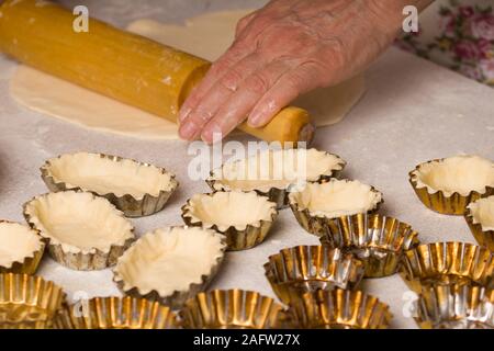 Rohteig in tartlet Dosen auf Backblech ungekocht Tortenboden in tartlet Dosen auf einem Backblech. redients zu Teig- und Törtchen Pfannen machen Stockfoto