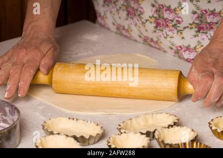 Frau Teig vorbereiten mit Rolling Pin auf rustikalen Holztisch Stockfoto