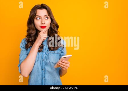 Foto von nachdenklich grübeln denken Freundin berühren Ihr Kinn holding Telefon mit Händen, Chancen, ihr Profil zu erhöhen. Stockfoto