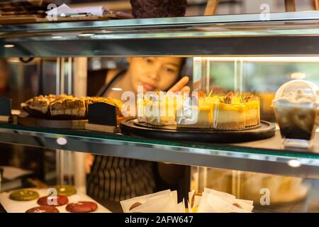 Zitronen Kuchen auf ein Schaufenster in einem Cafe mit Kellnerin im Hintergrund. Stockfoto