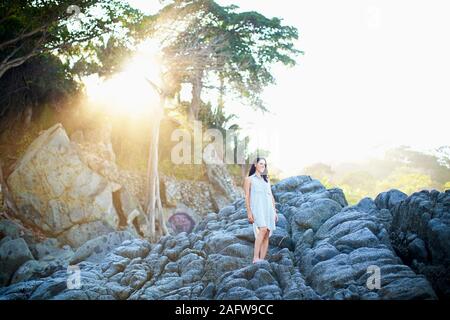 Ruhige Frau, die auf den Felsen unter sonnigen Baum, Sayulita, Nayarit, Mexiko Stockfoto