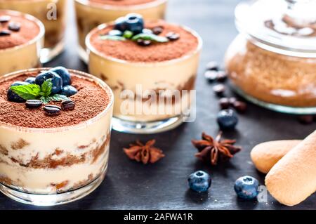 Dessert Tiramisu in Gläsern, mit Heidelbeeren und Minze mit Kaffeebohnen dekoriert, das Konzept der köstlichen Leben Stockfoto