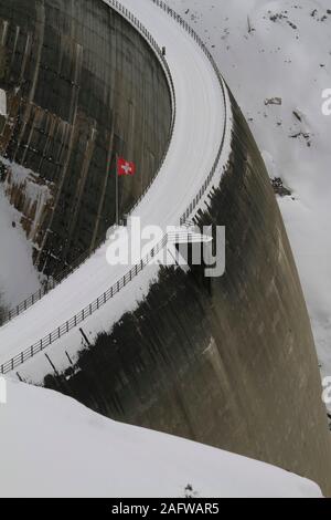 Schweizer Flagge über verschneite Dam, Vals, Kanton Graubünden, Schweiz Stockfoto
