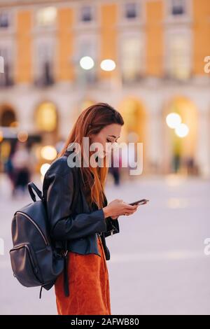 Junge Frau mit Rucksack mit Smart Phone auf städtischen Bürgersteig Stockfoto