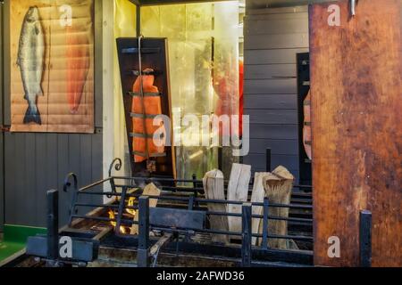 Holzkohle gegrillten Lachs auf einem freien Markt gekocht. Rote Scheiben geschnittenen Lachs auf offenen Holzfeuer im St Stephen Platz Weihnachtsmarkt vorbereitet. Stockfoto