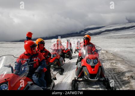 Menschen mit roten Helmen und Schals rot, Motorschlitten in Island auf einer tour auf dem Myrdalsjökull Gletscher Stockfoto