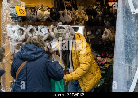 Kunden kaufen flauschige Ohrenschützer an der Winchester Weihnachtsmarkt neben der Kathedrale, Winchester, Hampshire, UK Stockfoto