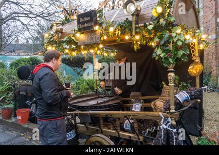 Kunden kaufen heiße Kastanien an der Winchester Weihnachtsmarkt neben der Kathedrale, Winchester, Hampshire, UK Stockfoto