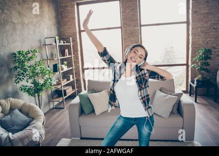 Foto von erstaunlich hübsche Dame hören Lieblingsmelodie in modernen Ohrenschützern tanzen in helle Zimmer in der Nähe von Sofa legere Kleidung Wohnung ÜBERGLÜCKLICH Stockfoto