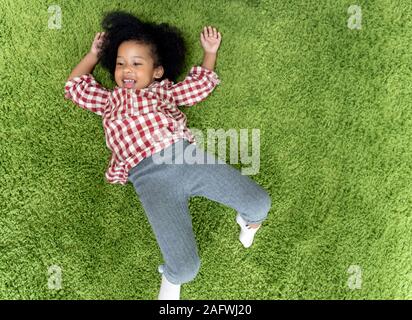 Glückliche Kinder Kinder lächeln und Festlegung auf grünem Teppichboden im Wohnzimmer zu Hause. Stockfoto