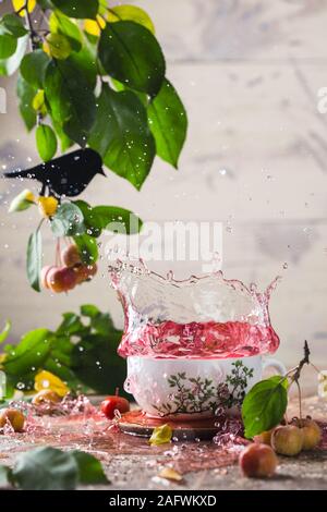 Splash in einem Porzellan Tasse roter Tee. Tee Zeremonie. Lackiert in China. In einem Raum mit grünem Laub eingerichtet Stockfoto