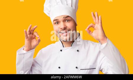 Happy Chef Mann deutete auf Ok stehen auf gelben Hintergrund, Panorama Stockfoto