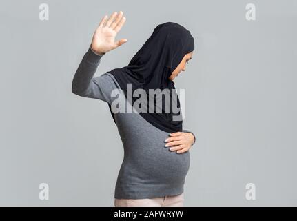 Angst schwanger muslimischen Frau im hijab Tun stoppen Geste, verstecken Gesicht Stockfoto