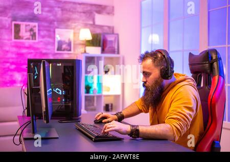 Konzentriert bärtigen Gamer am PC-Display suchen in Zimmer mit Neon Farben Stockfoto