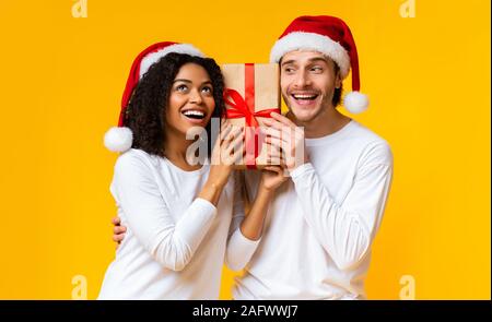 Portrait von glücklichen Paar hält Geschenkbox und tragen Nikolausmützen Stockfoto