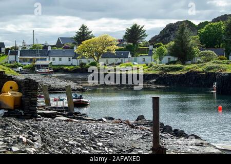 Den Hafen auf Easdale Island vor der Westküste Schottlands mit Schiefer Arbeitnehmer Cottages mit schroffen Hügeln hinter. Stockfoto