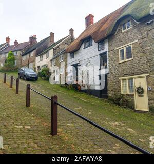 Auto auf steilen gepflasterten Straße mit strohgedeckten Hütten geparkt, Gold Hill, Shaftesbury, Dorset, Großbritannien im Dezember Stockfoto