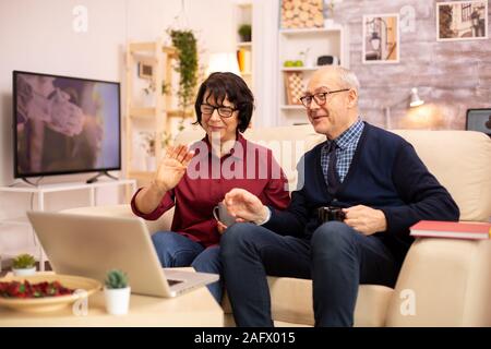 Ältere Ehepaar mit modernen Laptop mit ihren Enkel zu chatten. Großmutter und Großvater mit moderner Technologie Stockfoto