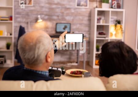 Rückansicht des älteren pensionierten Ehepaar bei einem Smartphone mit weißen isoliert Bildschirm schaut. Stockfoto